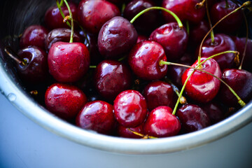 Red ripe cherries with twigs in a Cup and on the table