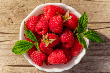 Freshly Picked Raspberries in a bowl on rustic wooden background.