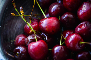 Red ripe cherries with twigs in a Cup and on the table