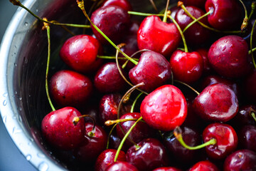 Red ripe cherries with twigs in a Cup and on the table