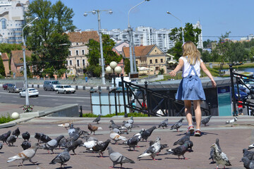 Girl running and many pigeons on the street