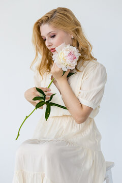 beautiful sensual girl with long blonde hair in dress with a bouquet of pink peonies flowers. Сoncept of feminity