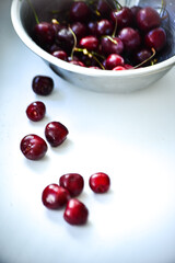 Red ripe cherries with twigs in a Cup and on the table