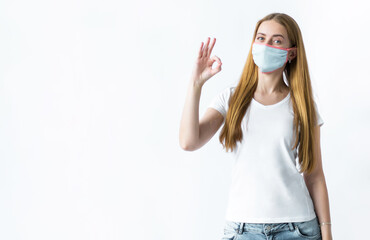 Young girl in a mask from the virus shows with his hand OK. The topic of coronavirus and safety