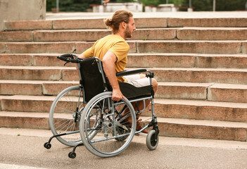 Young man in wheelchair near stairs outdoors