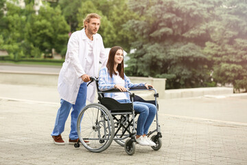 Doctor and young woman in wheelchair outdoors