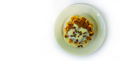 Baked waffles on a white plate. Covered with white sweet cream and chocolate.copyspace for text