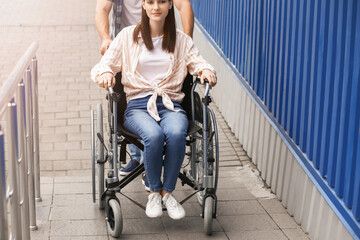 Obraz premium Young man and his wife in wheelchair on ramp outdoors