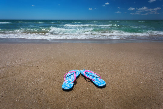 Flip-flops on the sandy beach. The concept of summer vacation. Flip-flops are blue with pink.