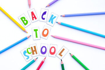 Back to school. Letters and colorful pencils on a white background. Flat lay. Education concept