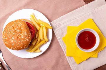 traditional fat burger and french fries on beige textile cloth