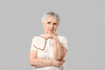 Stylish senior woman on grey background