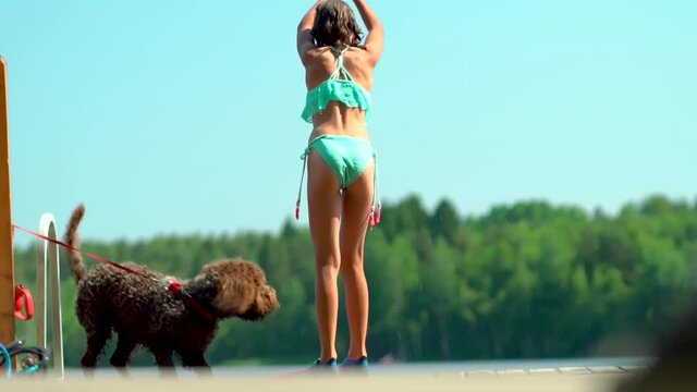 Girl jumping into the lake from wooden pier. Having fun on summer day. Teenager diving in to the water. Happy kid running and having fun at the beach. Active lifestyle concept. Summer vacation.