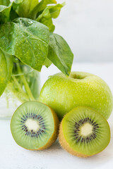 Fototapeta na wymiar Fresh green fruit on a white background, Apple, kiwi and spinach. The concept of natural green nutrition.