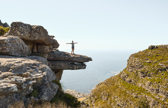 A girl standing on a rock overlooking the sea and the city of Cape Town, in Kasteelspoort hike, in Table Mountain Nature Reserve, South Africa.
