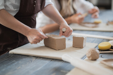 Female potter cutting piece of pottery clay using trimming tool close-up. Woman use clay cutter to a raw piece of clay