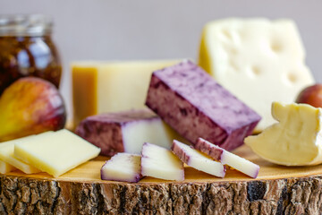Figs, fig spread, vine soaked cheddar and assortment of various types of cheese on wooden cutting board