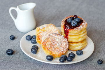 Syrniki or cottage cheese fritters with blueberry jam on a white plate