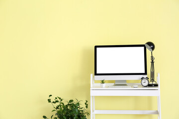 Modern PC monitor on table near color wall