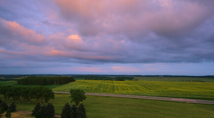 Blue-purple sky with clouds over green field