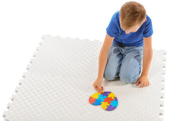 Little boy with autistic disorder doing puzzle on white background