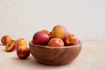 Bowl with ripe peaches on table