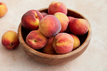 Bowl with ripe peaches on color background
