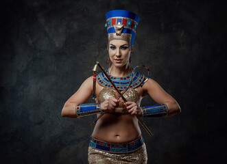 Young woman in egyptian costume posing in the studio with dark walls