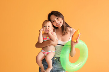 Mother and her little daughter with sunscreen cream and inflatable ring on color background