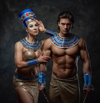 Sexy woman in traditional egyptian costume with her arm laid on male shoulder. Man holds egyptian signs of power. Both of them have blue and red bracelets.