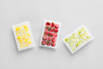 Trays with fruits in ice on grey background