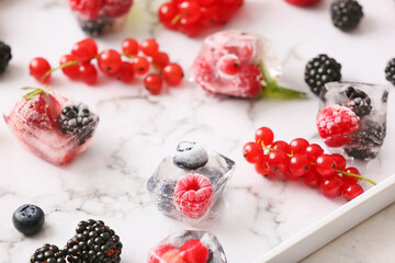 Ice with frozen berries on tray, closeup