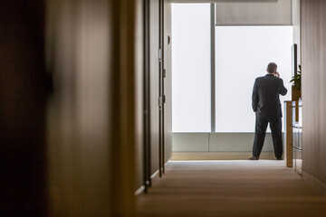 Rear view of businessman talking on phone while standing in corridor at office