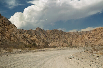 Transport and geology. Traveling along the dusty dirt road across the desert. The arid landscape with sandstone and rocky hills. 