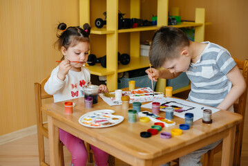 A boy and a girl play together and paint. Recreation and entertainment. Stay at home