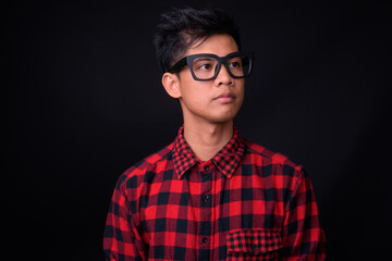 Portrait of young Asian hipster man against black background
