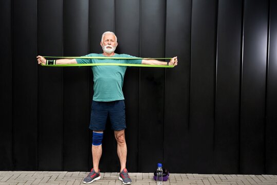 Senior sportsman exercising with resistance band