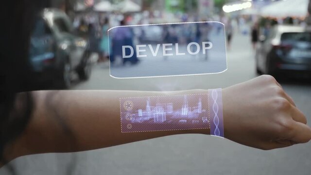 Female hand activates conceptual HUD holograms on smart bracelet with text Develop. Unrecognizable woman with holographic technology on a city street background