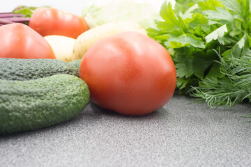 Fresh vegetables on a gray worktop, closeup: Potatoes, green onions, dill, tomato, parsley. Healthy food, vegan food.