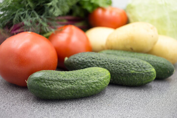 Fresh vegetables on a gray worktop, closeup: Potatoes, green onions, dill, tomato, parsley. Healthy food, vegan food.