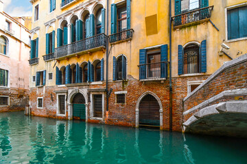 Fototapeta na wymiar A typical, picturesque and colorful residential canal at high water in the historic center of Venice, Italy with emerald green water.