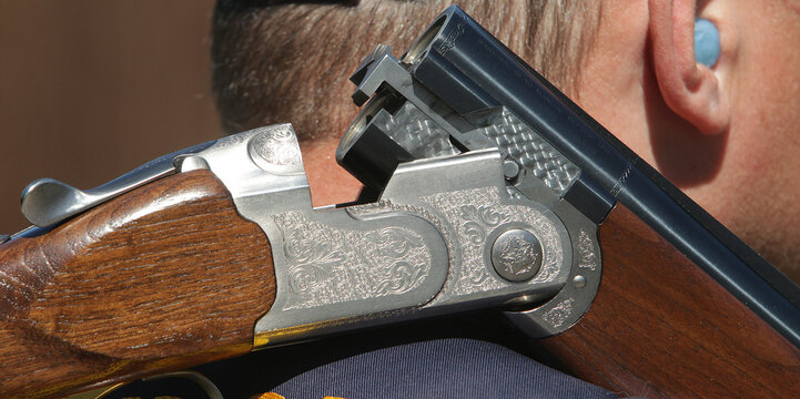 The hunter holds a two-barrel shotgun. Sports stelb on plates in the dash. Clay target shooter.