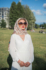 Portrait of an elegant girl in a white dress in a city park