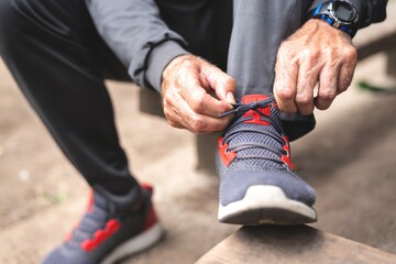 Senior man tying shoelace getting ready for workout - obrazy, fototapety, plakaty
