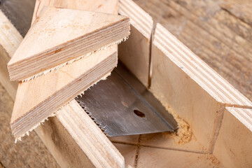 Cutting boards with a handsaw at an angle in the template. Minor carpentry work in the workshop. Light background.