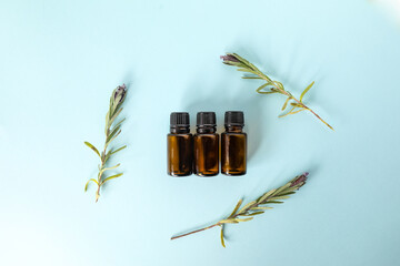 Flat lay image of three amber essential oil bottles surrounded by sprigs of fresh lavender