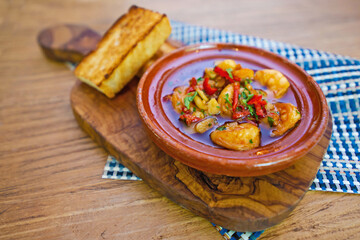 Spicy shrimps curry with bread in clay bowl 