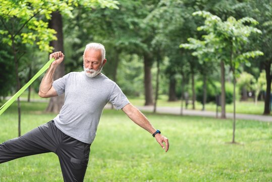 Senior Sportsman Exercising With Resistance Band At Park