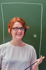 Happy woman teacher on green background. Door drawn in chalk on a blackboard. Concept welcome back to school