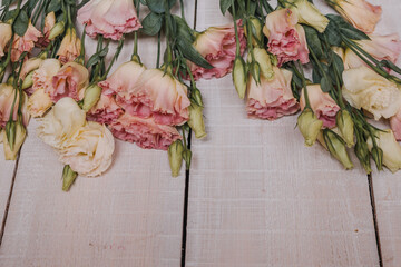 A bouquet of pink and white eustoms for a postcard, Wallpaper or poster. Eustoma flowers in pastel colors on a white wooden background made of boards in a close-up perspective with space for text.